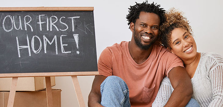 Couple sitting together next to a sign that reads 